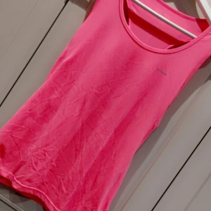 Rosa linnetopp från Adidas - Säljer en snygg och sportig rosa linnetopp.. Perfekt för träning eller en varm sommardag. Den är ärmlös och har en bekväm passform. Toppen är i ett lätt och andningsbart material.