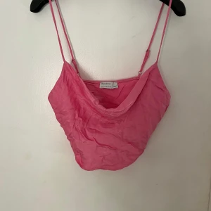 Rosa linnetopp från Bershka - Säljer en söt rosa linnetopp från Bershka. Den har tunna axelband och en lös passform, perfekt för sommardagar. Toppen är i ett lätt och luftigt material, vilket gör den superbekväm att bära. Passar både till vardags och fest!