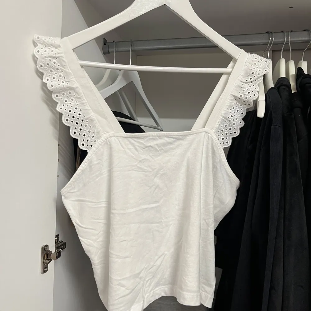 Säljer en superfin vit topp från H&M i storlek S, passar M. Den har vackra spetsdetaljer på axelbanden som ger en romantisk touch. Perfekt för sommardagar eller en avslappnad fest. Toppen är oanvänd och redo för nya äventyr!. Yläosat.