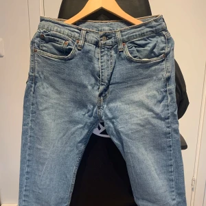 Levis jeans i ljusblå denim - Säljer ett par klassiska Levis 519 jeans i ljusblå denim. De har en normal passform och är i bra skick. Perfekta för vardagsbruk med en tidlös stil. Jeansen har fem fickor och en knappgylf.