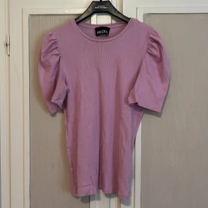 Rosa gullig topp - Säljer denna gulliga topp med små puffiga ärmar då det inte är min stil längre! Använd fåtal gånger så i nyskick och skön att ha på sig! Nypris: 199kr