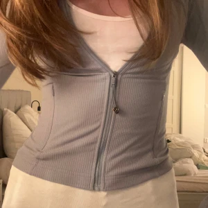 Ljusblå ribbad kofta med dragkedja - Säljer en snygg ljusblå kofta med dragkedja framtill. Den är ribbad och har en figurnära passform. Org pris= 1400kr