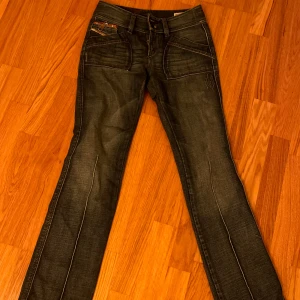 Jeans från Diesel - Snygga jeans från Diesel i en mörkblå tvätt. De har en klassisk femficksdesign med knappar på bakfickorna och en läderpatch med logga. De är nästan helt nya, köpta begagnade med lappen kvar. nypris $120 och sedan använda en gång. Tyvärr är de dock försmå och får därför säljas vidare.