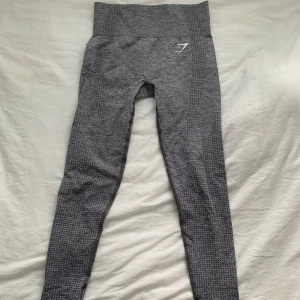 Grå leggings från Gymshark - Snygga grå leggings från Gymshark med hög midja och ett diskret mönster. Perfekta för träning med en tight passform som ger bra stöd. Materialet är stretchigt och bekvämt, vilket gör dem idealiska för intensiva träningspass.
