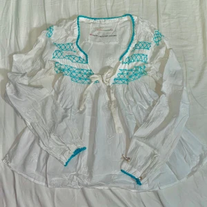 Odd Molly blus - En fin blus från Odd Molly med blåa sömmar och fina rosetter. Har dock defekt vid armhålan då det skett missfärgning vilket var svårt att fånga upp på kameran eftersom det är så pass lite. Skriv om ni har frågor!