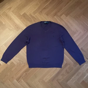 Lila tröja från Polo Ralph Lauren - Säljer en stilren lila tröja från Polo Ralph Lauren med v-ringning och broderad logga på bröstet. Tröjan har långa ärmar och är perfekt för en avslappnad men ändå elegant look. 100% Pima Cotton. Skriv vid frågor! 