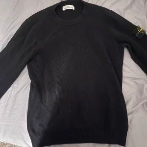 Svart tröja från Stone Island - Säljer en stilren svart tröja från Stone Island med deras ikoniska märke på ärmen. Tröjan är ribbad. Skick 9/10. Hållbart använd. Inga defekter