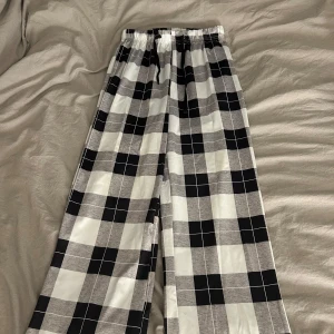 Rutig byxa med snörning - Snygga och bekväma byxor med svartvitt rutmönster. De har en elastisk midja med snörning för justerbar passform. Perfekta för en avslappnad stil. Material: siden! Dom är använda max 2 gånger och har inga skador!❤️