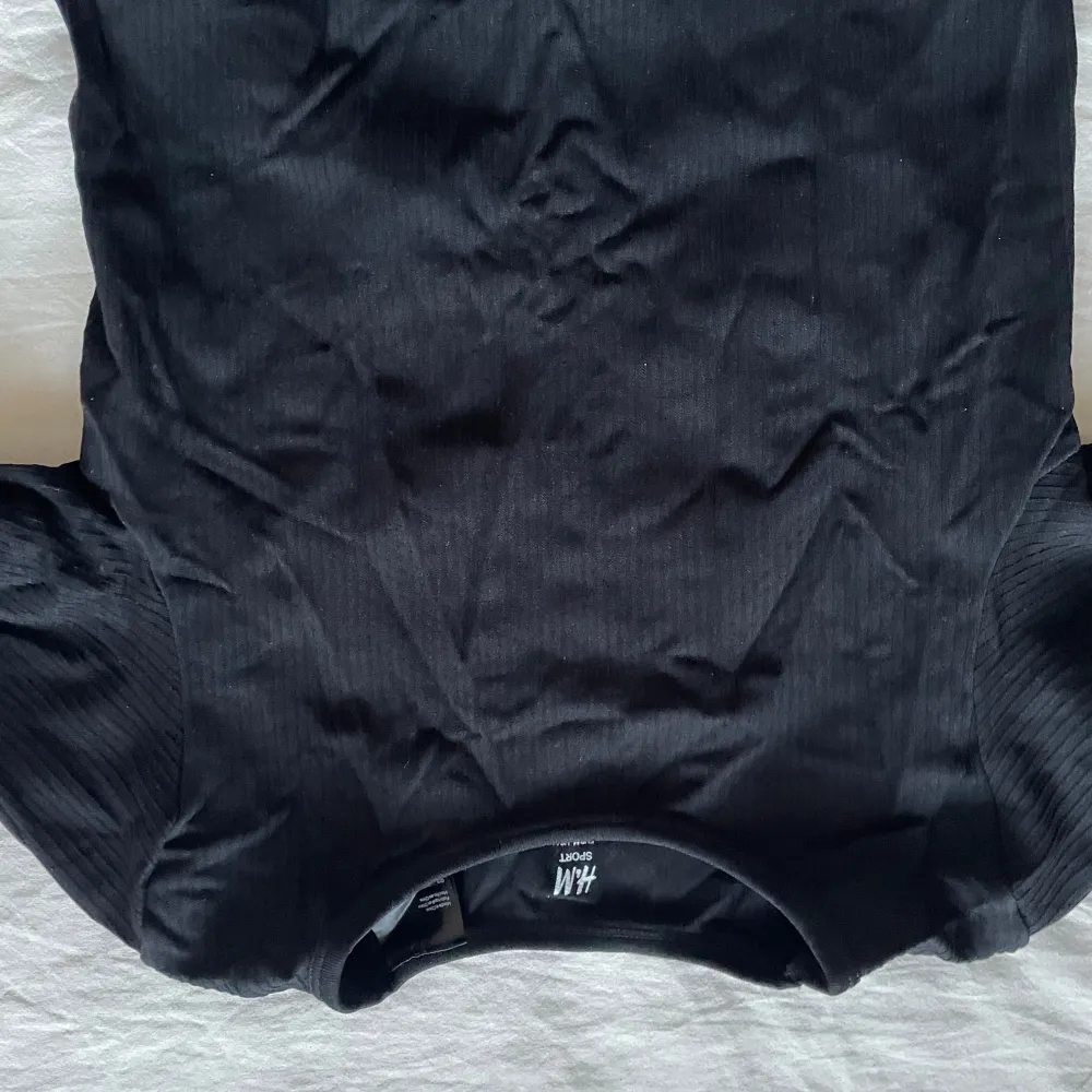 Snygg svart långärmad gym topp från H&M. Perfekt för en stilren look. Tillverkad i ett mjukt material som ger en bekväm passform.. Neuletakit & Villapaidat.