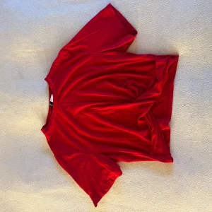 Röd t-shirt från H&M Divided - Säljer en röd t-shirt från H&M Divided. Den har en enkel design med korta ärmar och är tillverkad i ett mjukt material. Perfekt för en avslappnad stil.