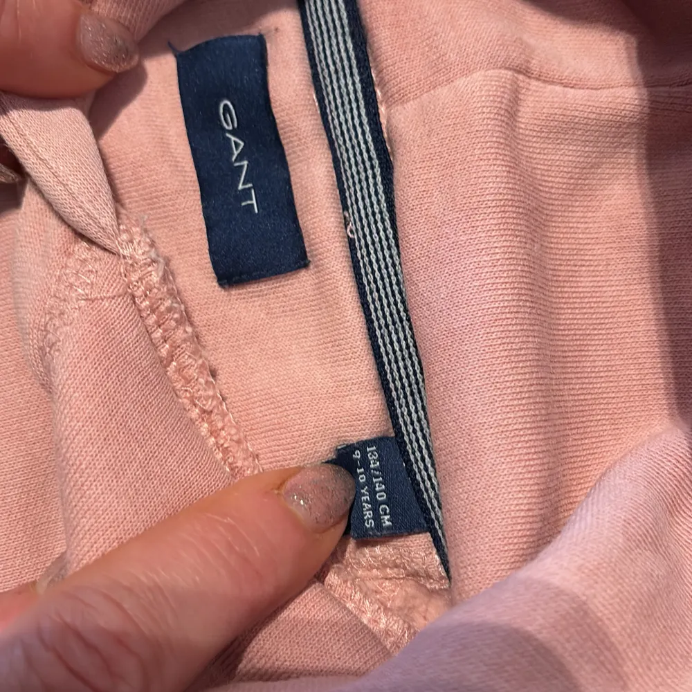 Säljer en snygg rosa hoodie från GANT med vit logotyp på bröstet. Tröjan har en klassisk känguruficka och en bekväm huva. Perfekt för en avslappnad stil.. Neuletakit & Villapaidat.