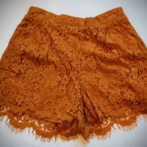 Senaps gula spets shorts - Senaps gula shorts i spets med blommigt mönster. Perfekta för en somrig look med fransiga kanter som ger en bohemisk touch.