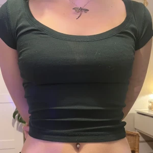 Mörkgrön croppad topp - Snygg mörkgrön croppad topp med korta ärmar och rund halsringning. Perfekt för en avslappnad stil.