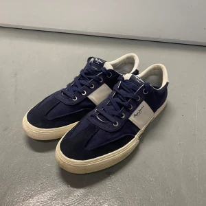 Blå sneakers från Pepe Jeans - Snygga blå sneakers från Pepe Jeans med vita detaljer och snörning. Perfekta för en avslappnad stil. Skorna har en klassisk design med en bekväm sula.