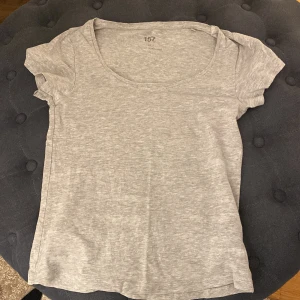 Grå t-shirt från 157 - Säljer en enkel och stilren grå t-shirt från 157. Den är kortärmad och har en rund halsringning. Perfekt basplagg för alla tillfällen. Sitter in i kroppsformen