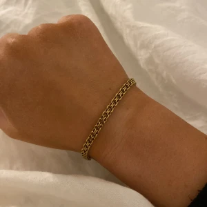 Guldarmband med flätad design - Elegant guldarmband med en fin flätad design. Armbandet har en säker låsning och passar perfekt för att ge en stilren touch till din outfit. Du får med mockberg förpackning.