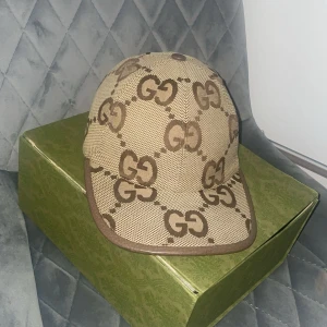 Beige Gucci keps jambo inga skador skriv vi intresse för o byta eller köp stolelk M ✅ - Snygg beige keps från Gucci med det ikoniska GG-mönstret i brunt. Kepsen har en klassisk design med böjd skärm och justerbar passform. Perfekt för att ge din outfit en lyxig touch.