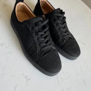 Svarta sneakers från Christian Louboutin - Snygga svarta sneakers i mocka från Christian Louboutin med den ikoniska röda sulan. Skorna har snörning och en stilren design som passar perfekt för en trendig look.   Priset kan diskuteras 