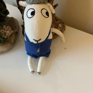 Mjukisdjur nalle Bu   - Charmigt  nalle Bu mjukisdjur med vita ben och armar, klädd i blå kläder. Perfekt som en söt dekoration eller leksak.magen finns tror jag ris korn ,armar och fötter rörelse,tyg material. Byxorna går att att tar av 