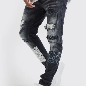 Svarta jeans med patchwork och slitningar - Snygga svarta jeans med unika patchwork-detaljer i vitt och svart. Jeansen har slitningar på framsidan som ger en cool och trendig look. Perfekta för dig som vill sticka ut med din stil. 