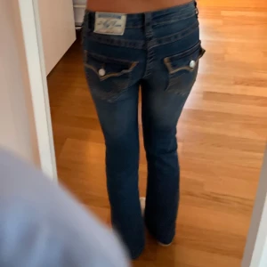Blå jeans från True Religion - Snygga blå jeans från True Religion med klassisk femficksdesign och kontrastsömmar. Jeansen är lowwaist, har en straight passform och är stretchiga. Mått: midja rakt över- 37cm, från grenen till midjekanten- 19cm, innerbenslängd- 77cm, ytterbenslängd- 98cm