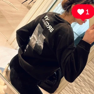 Svart sweatshirt med Brooklyn-tryck - Snygg svart sweatshirt med tryck av texten 'Brooklyn' och ett grafiskt motiv på framsidan. Tröjan har långa ärmar och en avslappnad passform, perfekt för en casual look. Passsr perfekt för s/m/l storlek