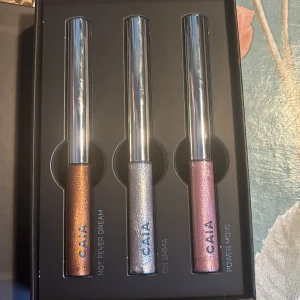 Ögonskuggor från CAIA - Set med tre glittriga ögonskuggor från CAIA i nyanserna Hot Fever Dream (brons), Oh Emma (silver) och Power Move (rosa). Perfekt för att skapa en dramatisk look med metallisk finish.