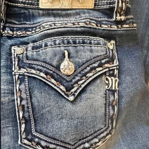 Blå jeans från Miss Me - Snygga blå jeans från Miss Me med unika detaljer på bakfickorna. Jeansen har en bootcut-stil och är dekorerade med broderier och knappar. Perfekta för en trendig look. storlek 29 Säljer pga fel storlek. Skriv för flera frågor 💕 kan gå ner i pris vid snabb affär