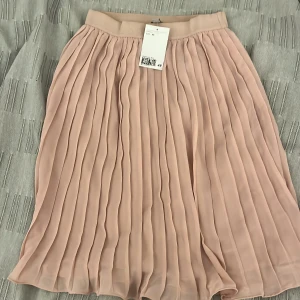 Rosa plisserad kjol från H&M - Rosa plisserad kortare kjol från HM, aldrig använd!