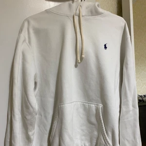 Vit hoodie från Polo Ralph Lauren - Säljer en stilren vit hoodie från Polo Ralph Lauren med den klassiska loggan broderad i marinblått på bröstet. Tröjan har en känguruficka och justerbar huva med snören. Perfekt för en avslappnad look. Pris kan diskuteras i chatten 
