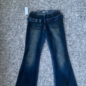 Lågmidjade jeans - Coola lågmidjade jeans utan fickor med en snygg skärp detalj runt. Finns bild på men lite försmå på modellen. Midjemått: ca 35 cm, ytterbenslängden ca 97 cm.☺️bootcut