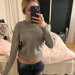 Grå tröja - Säljer en stilren grå tröja med långa ärmar och rynkade detaljer vid axlarna. Perfekt för en avslappnad look. Har en liten fläck men ingenting man lägger märke på. Skriv om ni har några frågor!💞