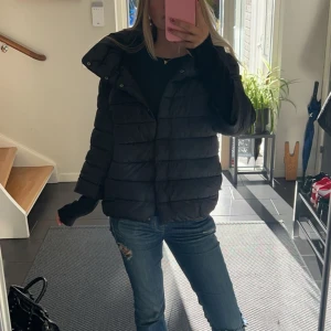 Svart pufferjacka - Säljer en svart pufferjacka som är perfekt för kyliga dagar. Jackan har knappar  framtill och trekvartsärm. Den är både stilren och bekväm, vilket gör den idealisk för höst och vinter. Passar bra till både vardags och lite mer uppklädda tillfällen.