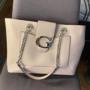 Guess väska - Säljer min rosa guess väska som aldrig kommer till användning väldigt fin, det är en liten fläck på insidan ifrån ett läppglans som rann ut! Priset går att diskutera 