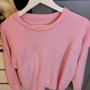 Rosa stickad tröja - Säljer en superfin rosa stickad tröja som är perfekt för både höst och vår. Den har en enkel design med långa ärmar och en rund halsringning. Tröjan är mjuk och bekväm, perfekt för mysiga dagar.
