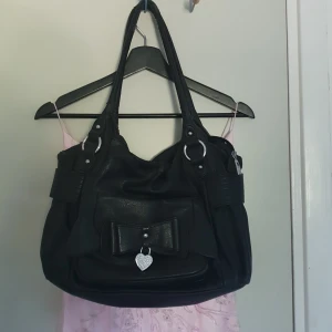 Svart söt väska - Söt väska med ett hjärta på. Presis så du får plats med t.ex skoldator. Flagnar lite men inget man tänker på