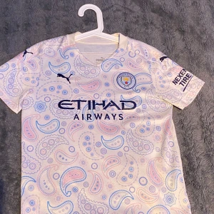 Manchester city tredjetröja 2020/21 - En mycket fin Manchester city tröja i storlek 152, väldigt bra skick fast den är använd, inga skador, nypris 699kr, det är Manchester citys tredje tröja ifrån säsongen 2020/21 med raheem sterling på ryggen Säljer pga för liten Kontakta mig vid frågor