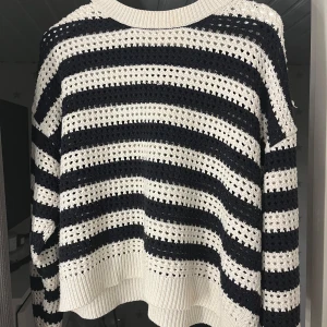 Randig stickad tröja från MNG - Säljer en superfin randig stickad tröja från MNG. Den är i svart/mörkblå och vit. Tröjan har långa ärmar och en bekväm passform. Lite fläckig vid kragen av tröjan.