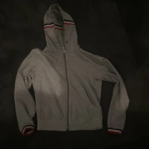 Moncler Hoodie - Grå Moncler Hoodie i storlek M. (Liten i storleken)  Tillkommer Kvitto från NK. Slarvat tyvärr bort snöret. 9/10 skick.
