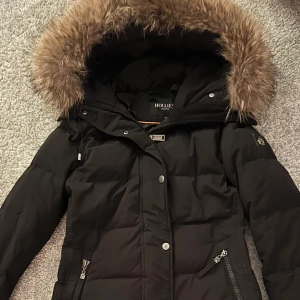 Hollies jacka - Super fin hollies jacka modell (subway) använd 1 månad under förra vintern.  Inga skador eller något som är trasigt.  Den håller värmen och man fryser inte under vintern.   För fler bilder skriv. Pris kan diskuteras