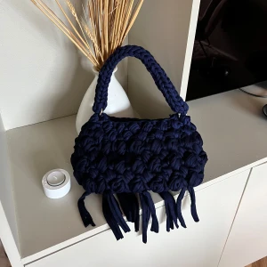 Virkad väska  - Stor, tung handstickad och gedigen handväska i marinblått t-shirt tyg. Detaljer som fransar och karbinhakar på axelrem bidrar till estetiken.  Aldrig använd, ny!  Nyansskillnad trots samma försäljare av garn. Medför karaktär skulle jag säga! 🤩