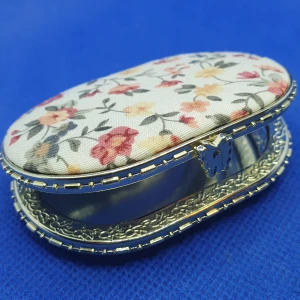 Söt fickspegel - Söt fickspegel med 2 spegelglas. Utsidan har ett mjukt blommigt tyg, knäppet är en liten fjäril och vackra mönster runt spegelglasen. Mått är ca: 7.5 × 6 cm. Denna finns i annan form/färg, se mina andra annonser. Perfekt att ha med sej i väskan.