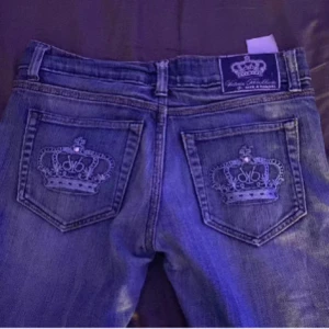  Victoria Beckham jeans  -  Ett par blåa Victoria Beckham jeans med blåa kronor på fickaora de är jättefint skick nästan aldrig använda. Skulle säga att de var lite mer i y2k