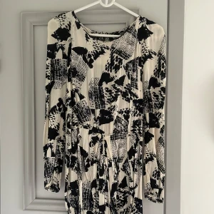 Svartvit mönstrad klänning från BikBok - Säljer en superfin svartvit klänning från BikBok i storlek XS. Klänningen har ett abstrakt mönster och långa ärmar, perfekt för både vardag och fest. Den är gjord i ett mjukt och bekvämt material. Passar perfekt till höst och vår!