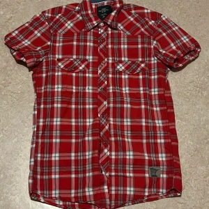 Röd rutig skjorta från H&M - Säljer en snygg röd rutig skjorta från H&M i storlek S. Skjortan har korta ärmar och knappar framtill. Aldrig använd i super skick. 