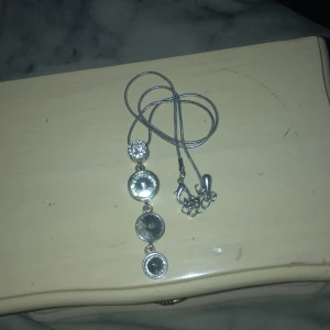 Silverfärgat halsband med hängande detaljer - Snyggt silverfärgat halsband med flera hängande detaljer i olika former. Perfekt för att ge en elegant touch till din outfit. Passar både till vardags och festliga tillfällen.