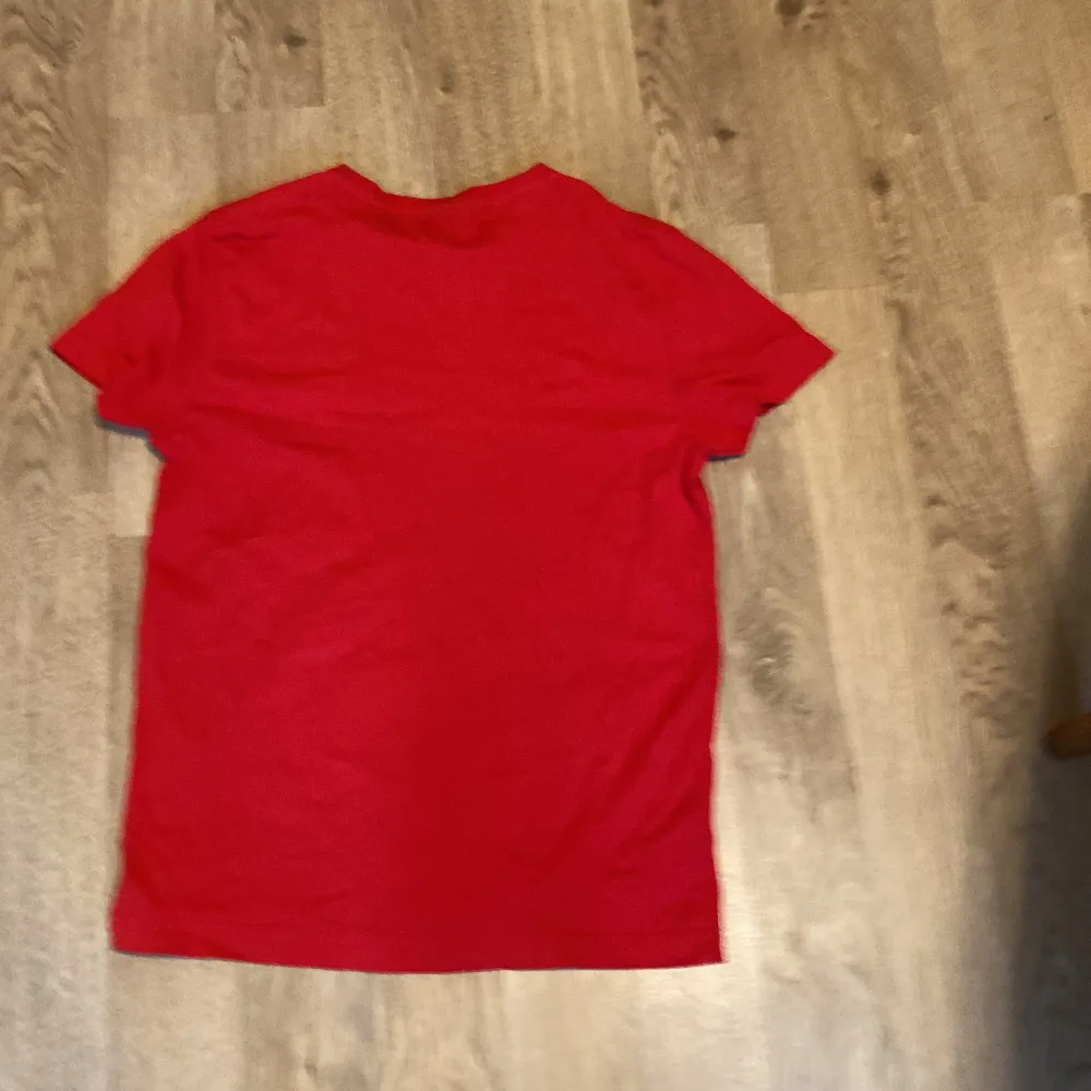 Säljer en snygg röd t-shirt från GANT passar i storlek S och M. Den är kortärmad och gjord av mjuk bomull. T-shirten har en liten logga på bröstet och är i nyskick. Passar både till vardags och festliga tillfällen. Skicka ett meddelande vid intresse! 🔥. T-shirts.