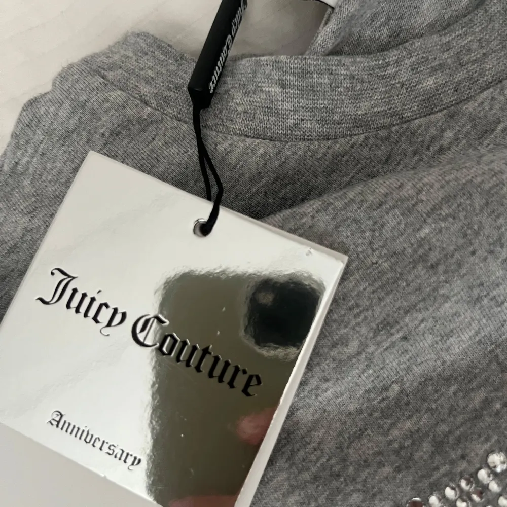 Snygg grå t-shirt från Juicy Couture i storlek S. Den är gjord av mjuk bomull och har ett glittrigt Juicy-märke på framsidan. Perfekt för en avslappnad men ändå stilren look. Passar bra till både jeans och kjol!. T-shirts.