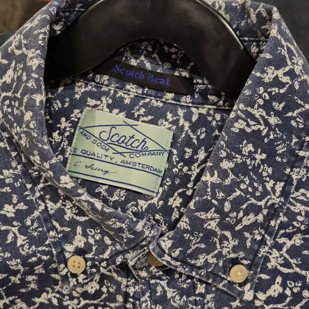 Säljer en snygg blommig skjorta från Scotch & Soda i storlek M. Skjortan är mörkblå med vita blommor och har långa ärmar. Den är gjord av 100% bomull och har knappar framtill. Perfekt för både vardag och fest!. Skjortor.