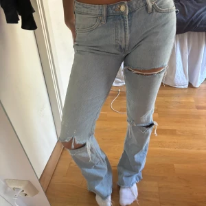 Ljusblå jeans med slitningar - Säljer ett par ljusblå jeans med coola slitningar på knäna. De har en klassisk femficksdesign Perfekta för en avslappnad vardagslook. Passar bra till sneakers eller boots!